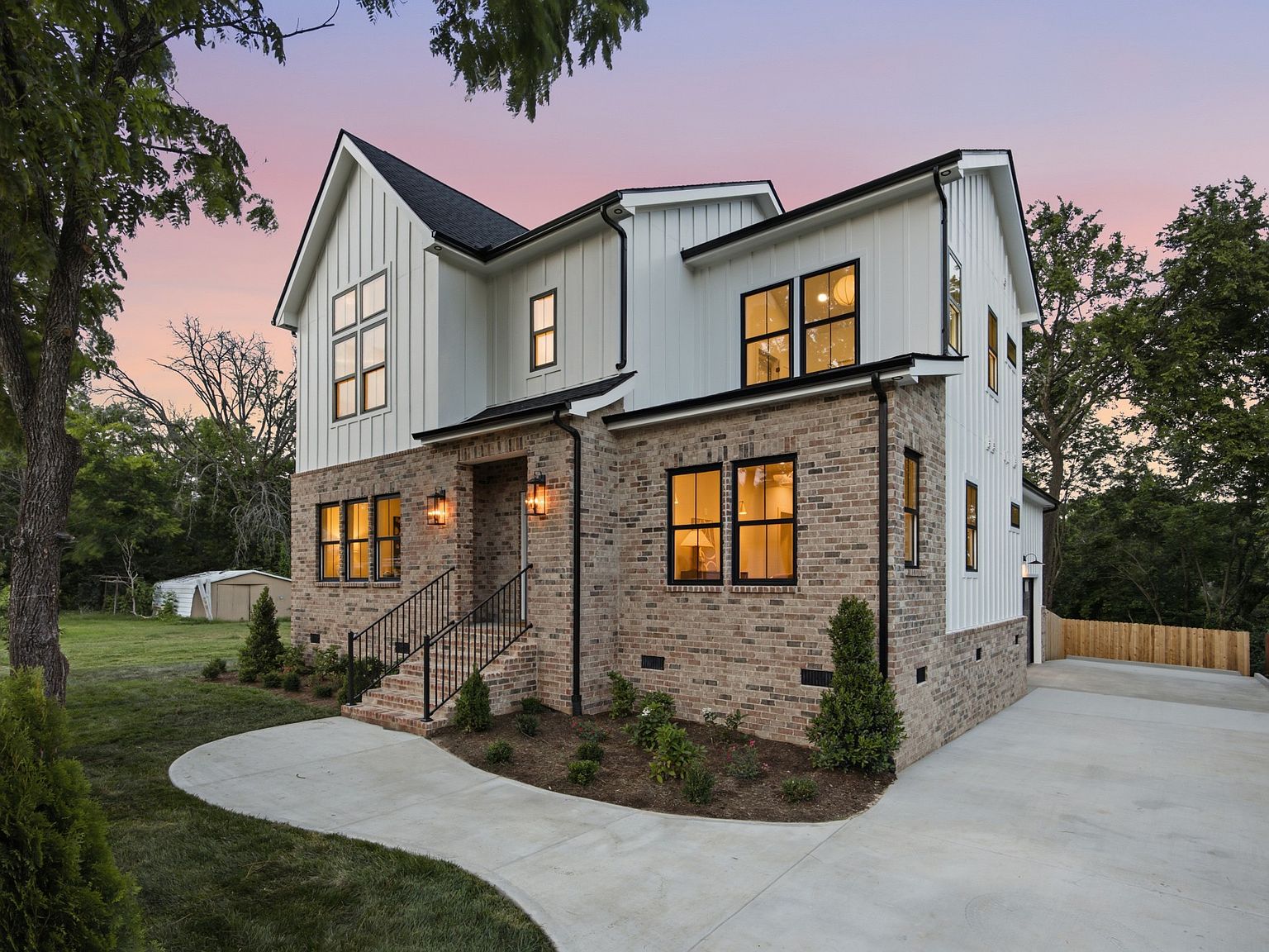 Finished Tan Development home in Inglewood at dusk, brick and white board-and-batten siding lit from within