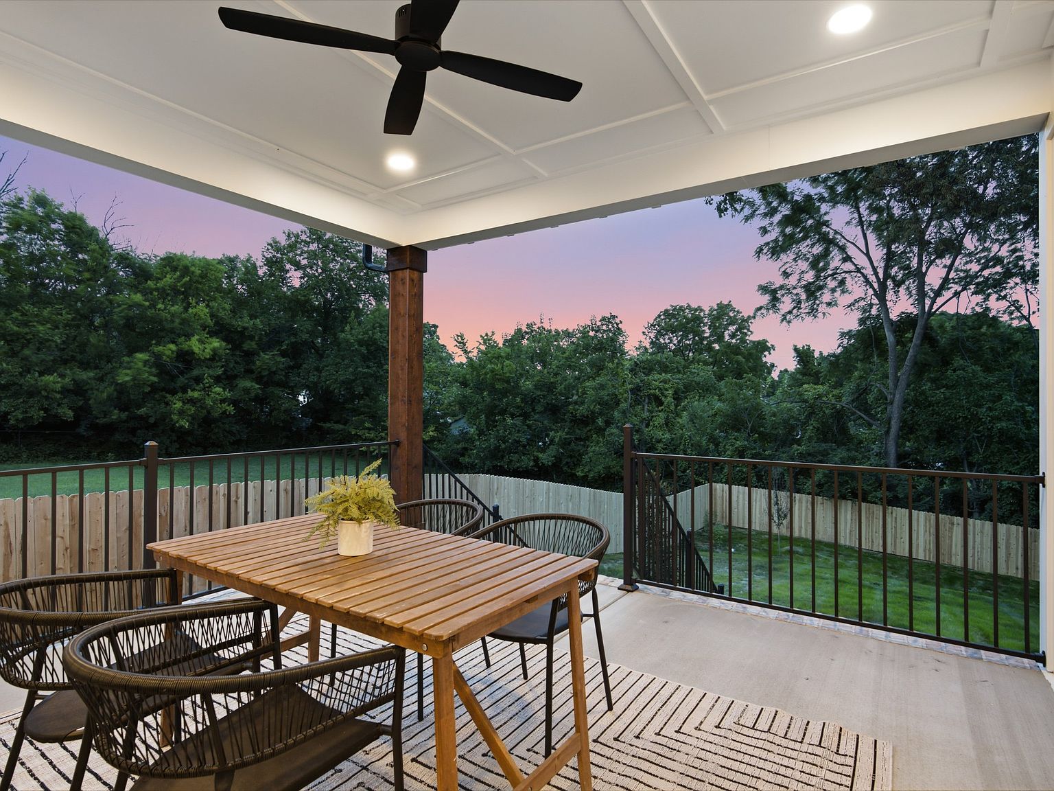 Covered back deck with a wood ceiling fan overlooking the fenced yard