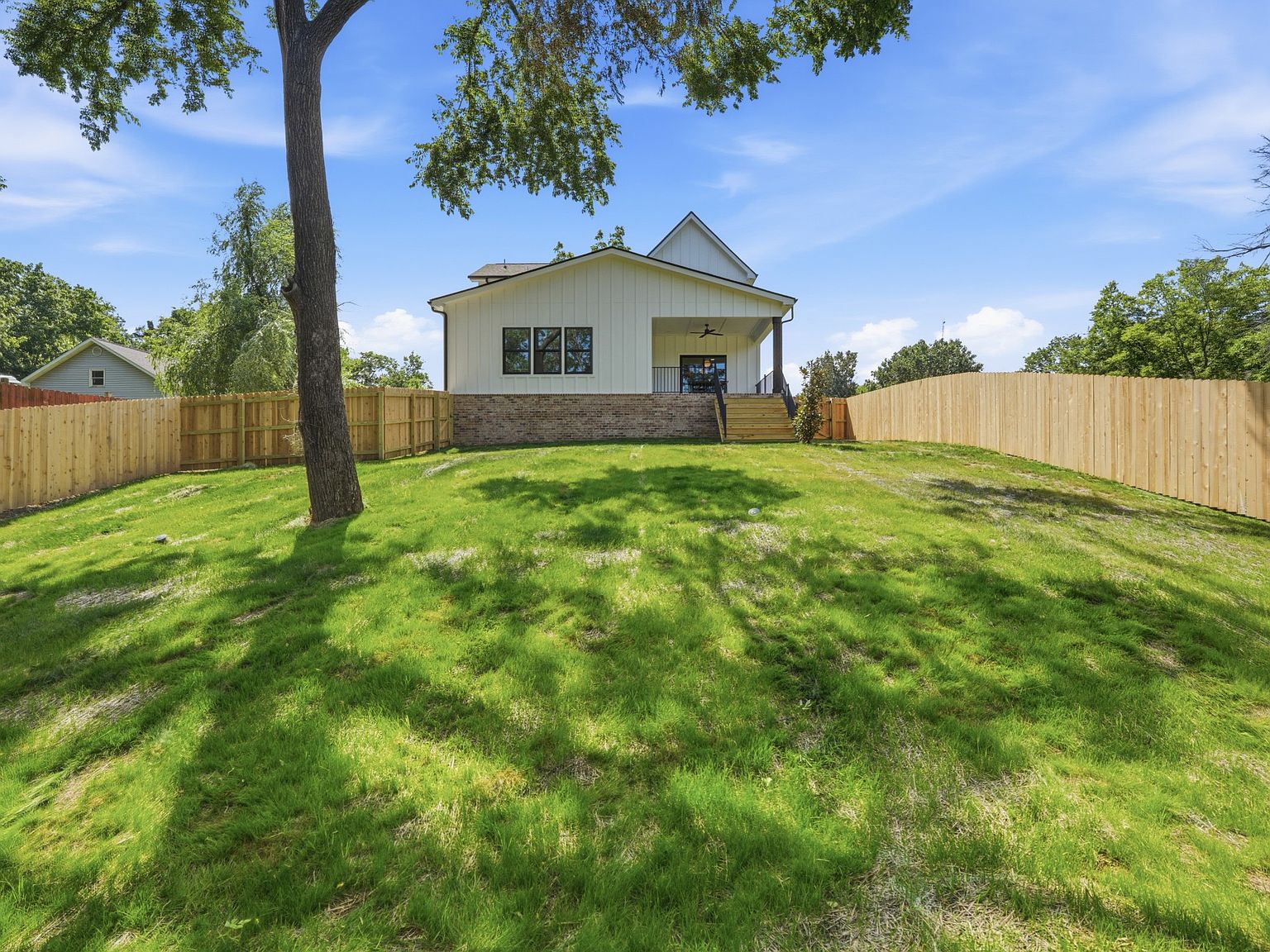 Rear exterior and sloped backyard framed by mature trees