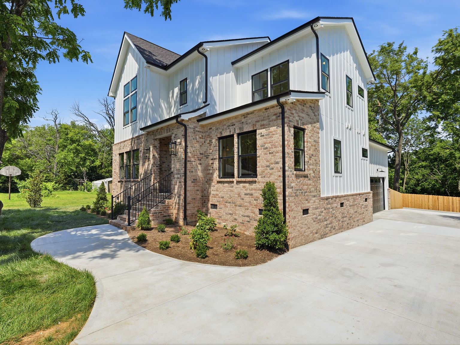 Modern farmhouse exterior in Inglewood with white board-and-batten siding, mixed brick veneer, and black steel windows